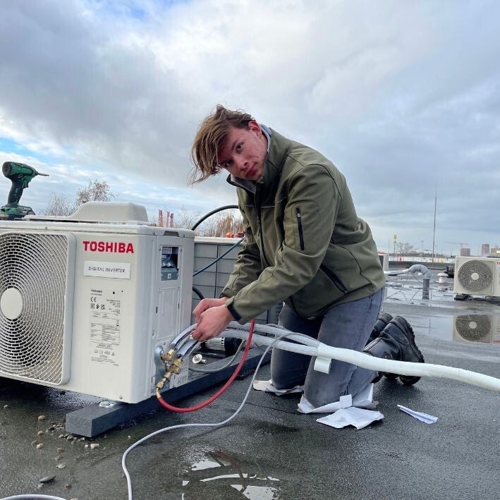 Van den Beucken controleert een buitenunit met meetapparatuur