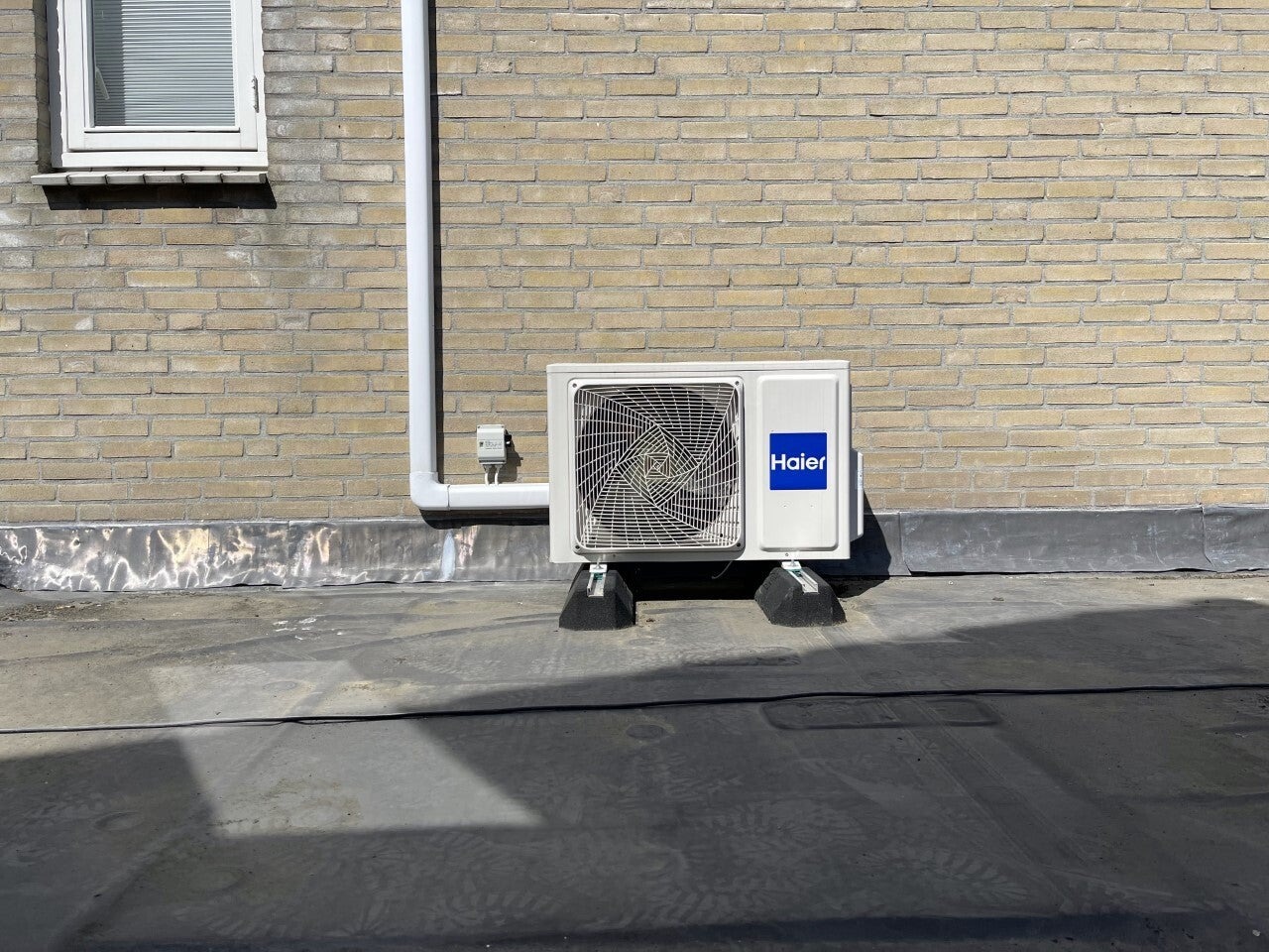Airco-buitenunit naast een bakstenen gevel